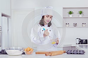 Female baker whisking eggs in a bowl to make cakes