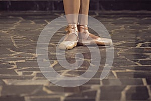Female Ballet Dancer Legs In Laced Pointes Shoes. Posing With Straight Legs Outdoors On Tile Floor