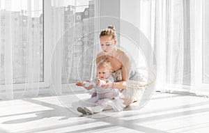 Female ballet dancer teaching little girl doing exarcises for stretching