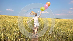 Female with balloons having fun in field in slowmo