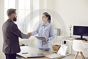 Female bank manager exchanging handshake with business client after meeting in office