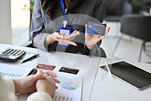 Female banker explaining the privileges of a new credit card to her customer during the meeting