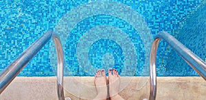 Female bare feet standing on the edge of swimming pool half ready to enter