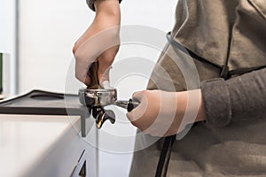 Female barista hand making espresso from ground coffee in a modern cafe