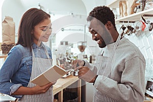 Female barista making notes while her colleague scrutinizing portafilter