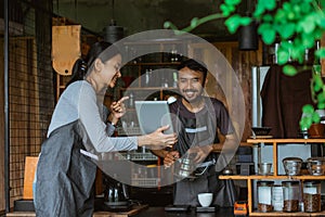 female barista showing the digital tablet at the male barista