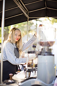 Female barrista making coffee for clients