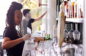 Female Bartender Cleaning Glasses With Cloth Behind Bar