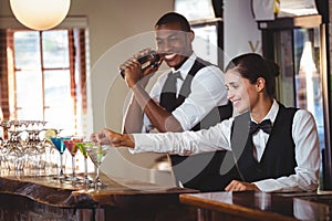 Female bartender garnishing cocktail with olive