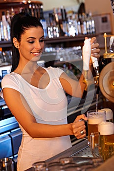 Female bartender tapping beer in bar