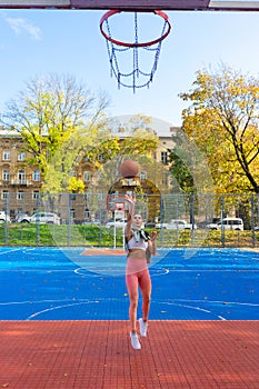 Female basketball player in jump throws the ball into the basket.