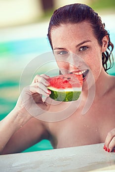 Female bather refreshing in pool with watermelon