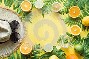 Female beach straw sunhat, sunglasses, citrics on yellow. Top view. Summer travel concept