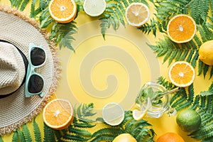 Female beach straw sunhat, sunglasses, citrics on yellow. Top view. Summer travel concept