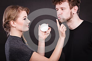 Female beautician apply cream on male mouth.