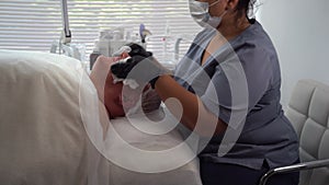 female beautician cleaning the face of an elderly man with a napkin. Man caring for facial skin in a beauty salon. Male