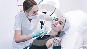 The female beautician doctor making injection in young woman face. The doctor cosmetologist doing facial contouring procedure