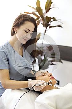 Female beautician using machine for microcurrent treatment