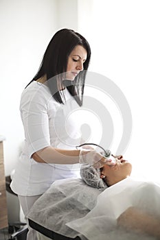 Female beautician using machine for radiofrequency lifting
