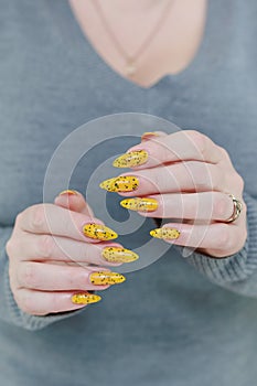 Female beautiful hand with long nails and a yellow nail polish