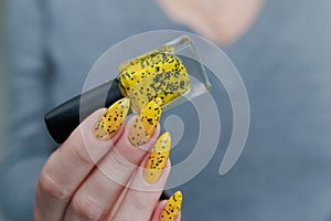 Female beautiful hand with long nails and a yellow nail polish