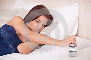 Female in bed sullenly look at clock photo