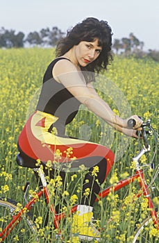 Female bicyclist resting in field of Spring flowers, Malibu, CA