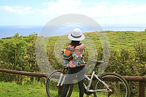 Female biker admiring the scenic Pacific ocean from Rano Kau volcano on Easter Island, Chile