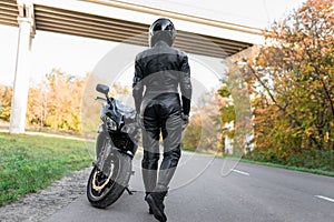 Female biker girl stands near the motorcycle.