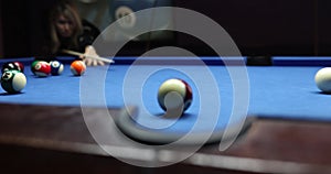Female billiard player shots ball to push goal into pocket