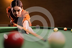 Female billiard player using the cue stick while playing billiard at the club. Playing billiards