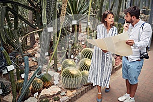 Female biologist explaining map to a male tourist in botanical garden