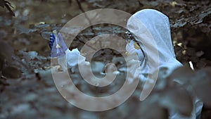 Female biologist in protective uniform holding infected water sample, poisoning