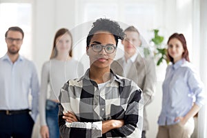 Female black millennial employee standing foreground arms crosse