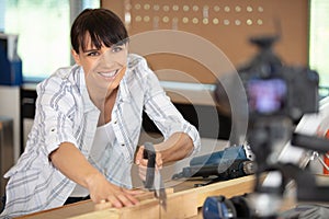 female blogger using handsaw filming carpentry tutorial