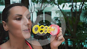 Female blowing soap bubbles in the garden by the pool, slow motion