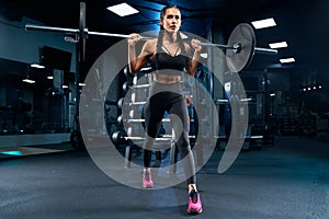 Female bodybuilder doing lunges using barbell in gym.