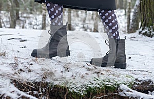 Female boots on snowy path, side view. Legs walking or strolling in winter forest in funny cute tights with hearts print for 14