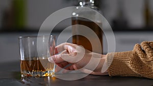 Female boozer`s hand pouring alcohol into glass