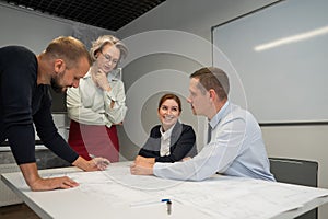 The female boss evaluates the work of subordinates. Designers engineers at a meeting.