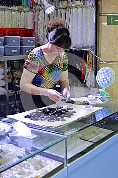 Female boss finishing black gem amulet in liwan jade jewelry market