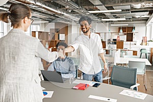 Smiling female boss leader shaking hand of new team member recruiting him for job on staff briefin