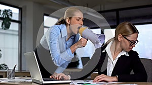 Female boss screaming with megaphone at colleague, authoritarian leadership