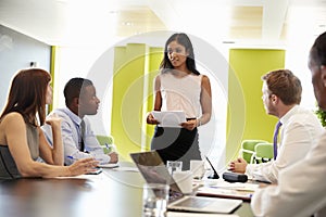 Female boss stands holding document at informal work meeting