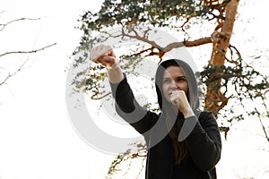 Female boxer is boxing in the park. Young woman is training a direct hit, focus on eyes