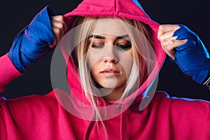 Female boxer with bruise over her eyes and wounds on lips in pink hoodie