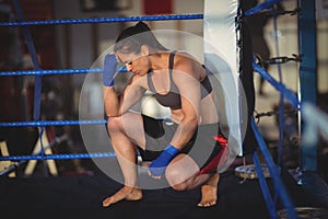 Female boxer crouching in boxing ring
