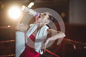 Female boxer drinking water in boxing ring