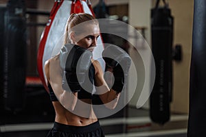 Female boxer in gloves standing in defense pose and looking focused a side