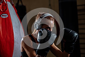 Female boxer in gloves standing in defense pose and looking focused a side